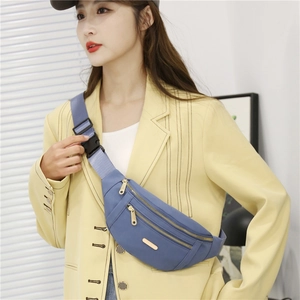 Detail of light blue PU waist bag with dual metal zippers worn on yellow blazer