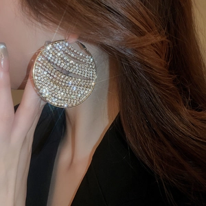 Macro detail of large geometric hoop earrings with sparkling white zircons on model