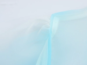 Dettaglio del tessuto in organza sfumata blu e bianca con morbida trama a pieghe