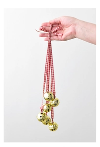 Detail of gold metal Christmas bells with star cutouts and red-white plaid ribbon