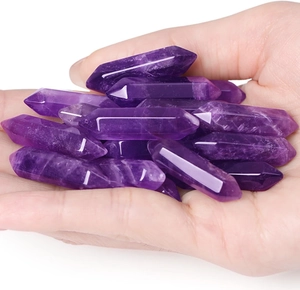 Detailed view of polished natural amethyst hexagonal prisms held in hand showing texture