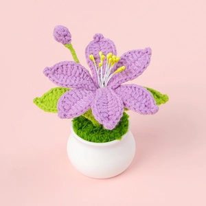 Close-up of handmade crochet purple lily potted plant with green leaves and a white pot