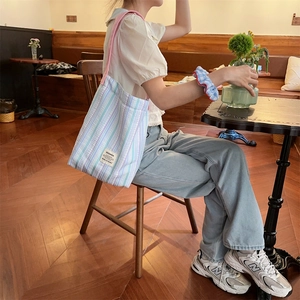 Gros plan du sac cabas en toile rayée avec bandoulière rose et étiquette de marque