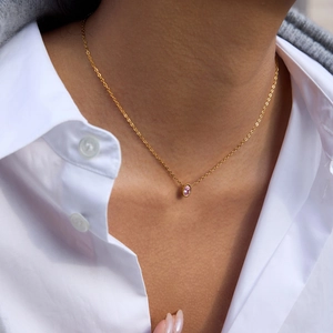Détail du collier en or 18k avec zircon rose porté sur une chemise blanche
