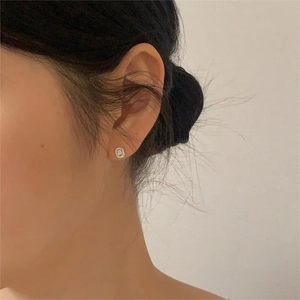 Close-up of minimalist sterling silver square zircon stud earring worn on model's ear