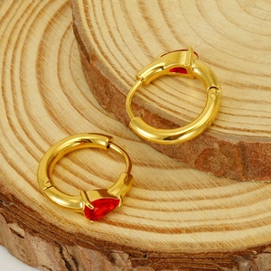Golden pear-shaped red gemstone hoop earrings in stainless steel on a wood base