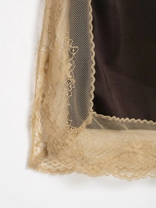 Detailed close-up of dark brown silky fabric with elegant golden lace trim embroidery