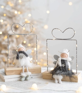 Close-up of Christmas angel plush dolls on wood bases with LED heart shaped metal stands