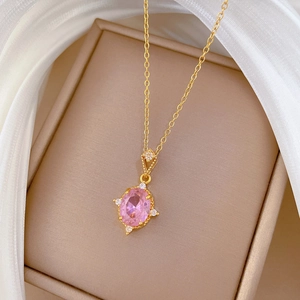 Macro view of gold chain necklace with pink rhinestone pendant on a jewelry gift box