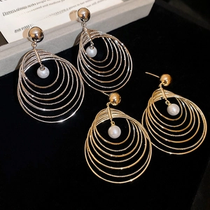 Detail of layered gold and silver circle drop earrings with pearls on black velvet