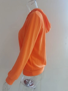 Detalle de una sudadera con capucha naranja brillante con una textura de canalé vertical