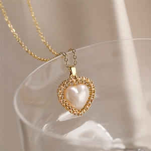 Close-up of gold-plated heart pendant with pearl center on elegant silk fabric