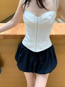 Detail of white lace corset top with 3D embroidery and black puff skirt on a model