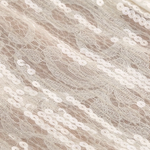 Détail des paillettes blanches et de la texture de dentelle sur une robe de soirée chic