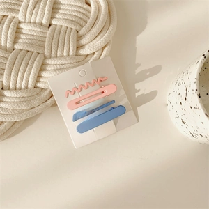 Detailed view of pink and blue wave-shaped hair clip set on a white card display