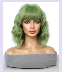 Detail of green short wavy bob wig with bangs on female mannequin in studio lighting