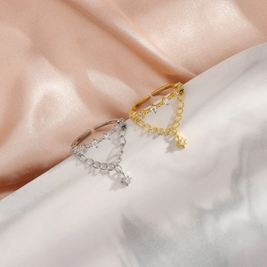 Detail of double-layer chain ring with star pendant and zircon inlays on pink satin