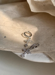 Close-up of sparkling cubic zirconia cross pendant earrings on vintage beige paper background