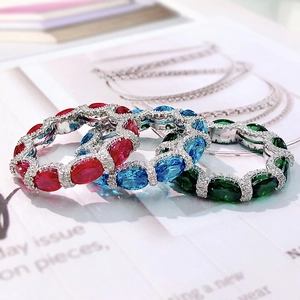Close-up of stacked silver rings featuring oval red, blue, and green gemstones on magazine