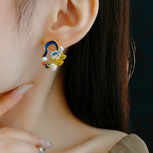 Close-up of vintage floral earring with enamel petals and freshwater pearl on ear