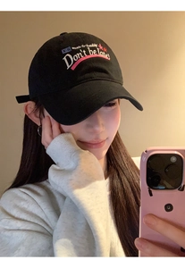 Detail of black baseball cap featuring pink and white embroidery Don't be late