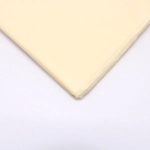 Close-up of pale yellow tissue paper texture with clear folded corners on white background
