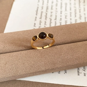 Detail shot of vintage 18k gold tiger eye ring resting on velvet stand and retro book