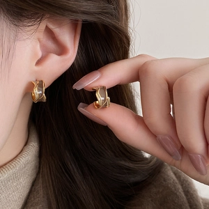 Chic C-shaped metal stud earrings with brown enamel inlay on female model ear