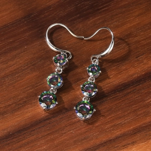 Elegant silver drop earrings with three round gradient rainbow zircon stones on wood background