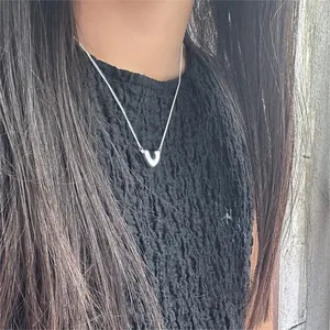 Close-up of a minimalist silver V-shaped pendant necklace on a model wearing black