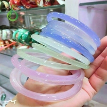Detail showing various colors of translucent icy agate chalcedony bangles on a wrist