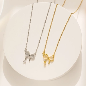 Detailed close-up of bow-knot pendants with cat eye stones in silver and gold finishes