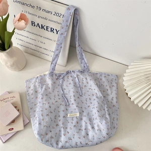 Detail of light blue floral tote bag with ribbon tie and white woven brand label