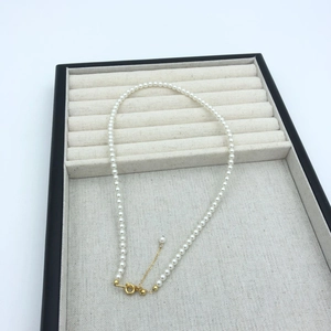 Detail view of round white pearl necklace with adjustable 14k gold plated clasp