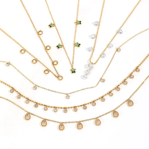 Détail de six colliers dorés avec pendentifs en zircon vert et breloques papillon