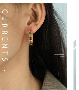 Close-up of gold hoop earrings set with colorful rectangular-cut rainbow gemstones