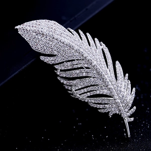 Macro view of silver feather brooch with sparkling zircons against a black background