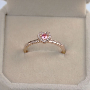 Close-up of rose gold heart ring with pink gemstone in a beige velvet jewelry box
