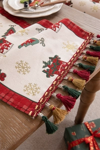 Detail of woven Christmas table runner with reindeer, snowflakes, and festive tassels
