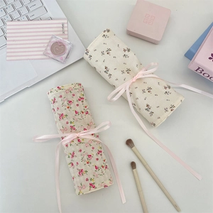 Floral fabric makeup brush organizer pouch with elegant silk ribbon closure on white desk