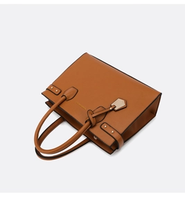 Detail of brown faux leather tote bag featuring pebble texture and gold fashion lettering