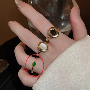 Detailed view of a vintage gold-plated ring set featuring opal and emerald green beads