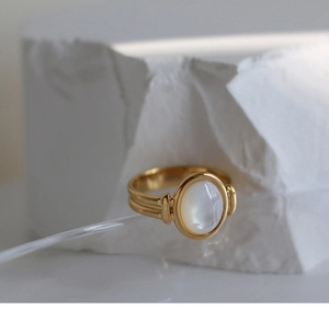Detailed close-up of a gold ring featuring a white mother of pearl inlay on a stone stand