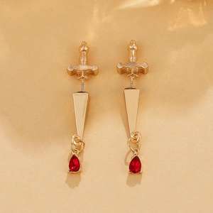 Detailed shot of golden gothic sword earrings with red teardrop crystal pendants