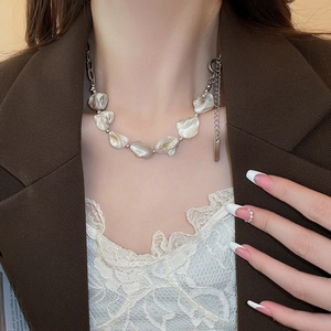 Dettaglio di una collana minimalista con perle di madreperla e catena d'argento sul collo