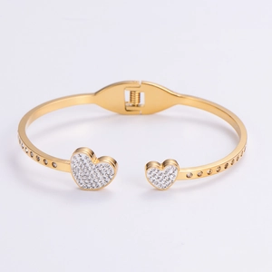 Detail of a golden open heart bracelet featuring sparkling pavé crystals on a white background