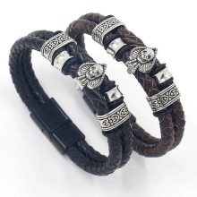 Detail of black and brown braided leather bracelets with metal skull and magnetic clasps