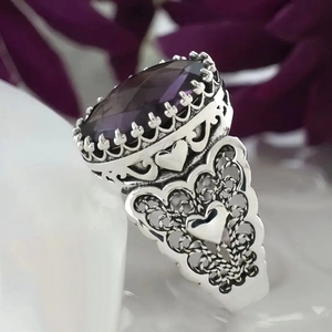 Detail van vintage zilveren ring met grote paarse ovale steen en hartvormig filigraan
