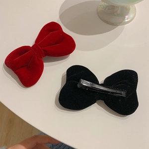 Detail of red and black velvet bow hair clips showing secure metal alligator clip structure