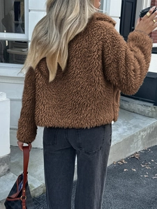 Street style view of the back of a short brown faux fur teddy coat with grey jeans